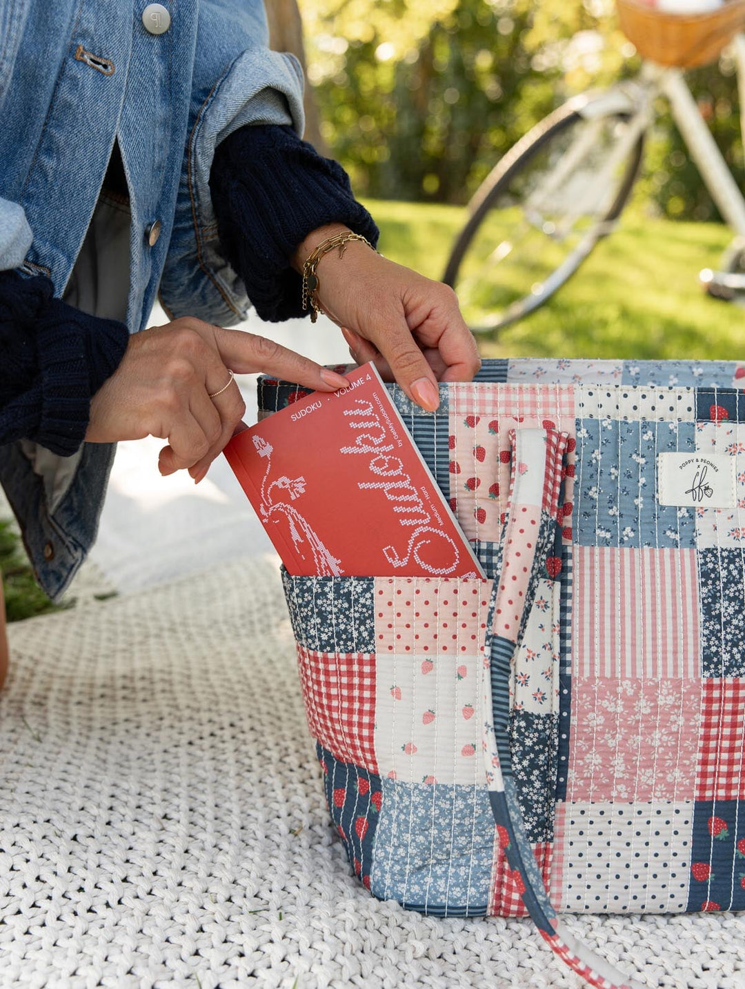 Poppy & Peonies Analog Tote in Strawberry Patchwork exterior pocket close-up, showing a book being placed into the large front slip pocket.