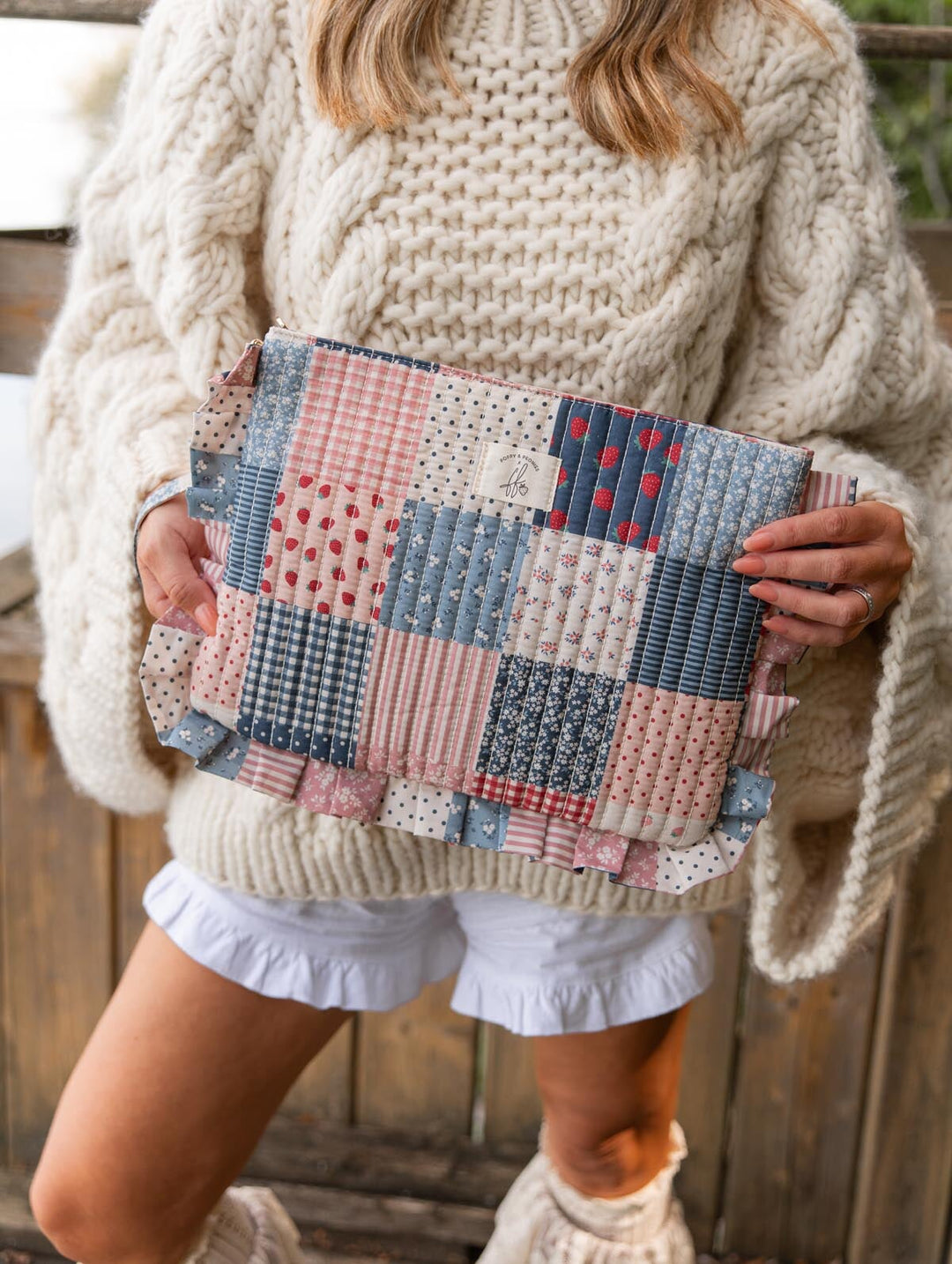 Poppy & Peonies 2-Piece Darling Ruffle Set in Strawberry Patchwork lifestyle view, featuring a quilted blue, pink and cream patchwork pouch with playful ruffle trim, held by a woman.