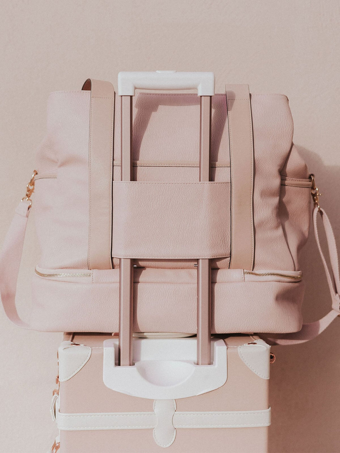 Blush travel bag with a trolley sleeve on a pink suitcase