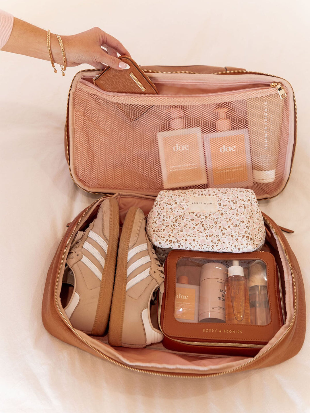 Open travel bag compartment with shoes and toiletries on a light background