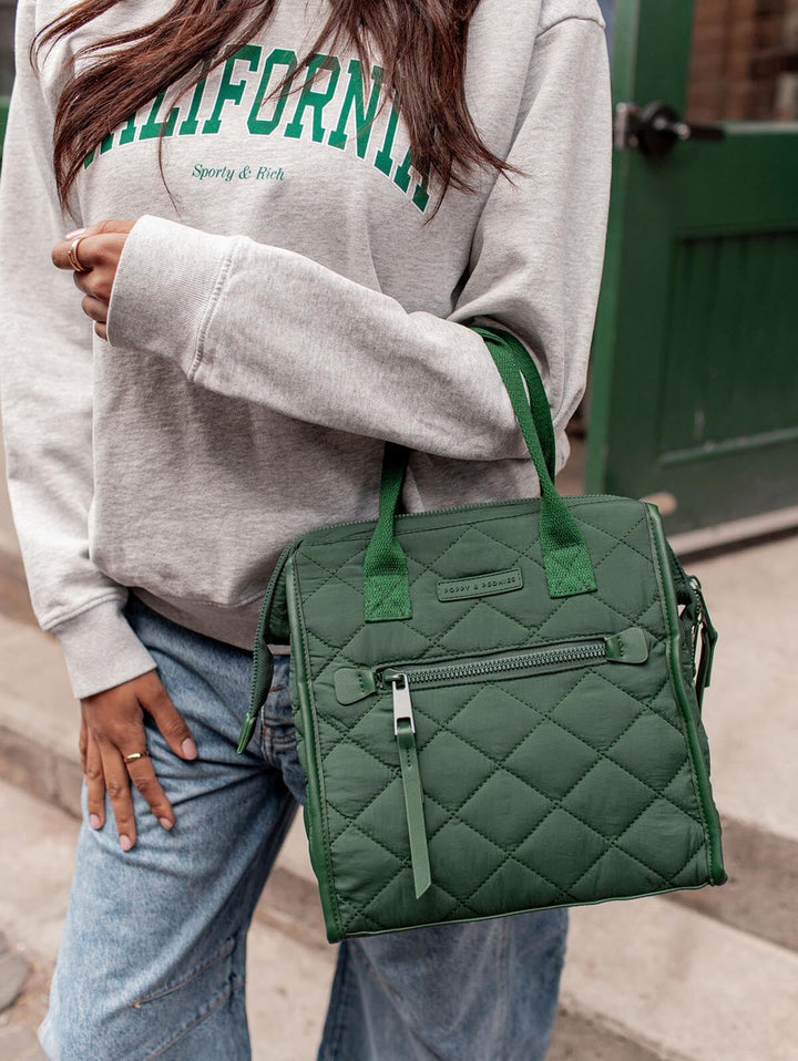 Person wearing a grey sweatshirt with 'California' text, holding a green quilted lunch bag
