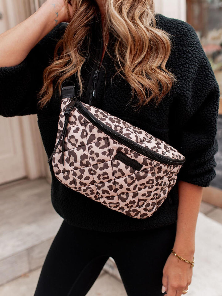 Person wearing a leopard print crossbody bag with a blurred background