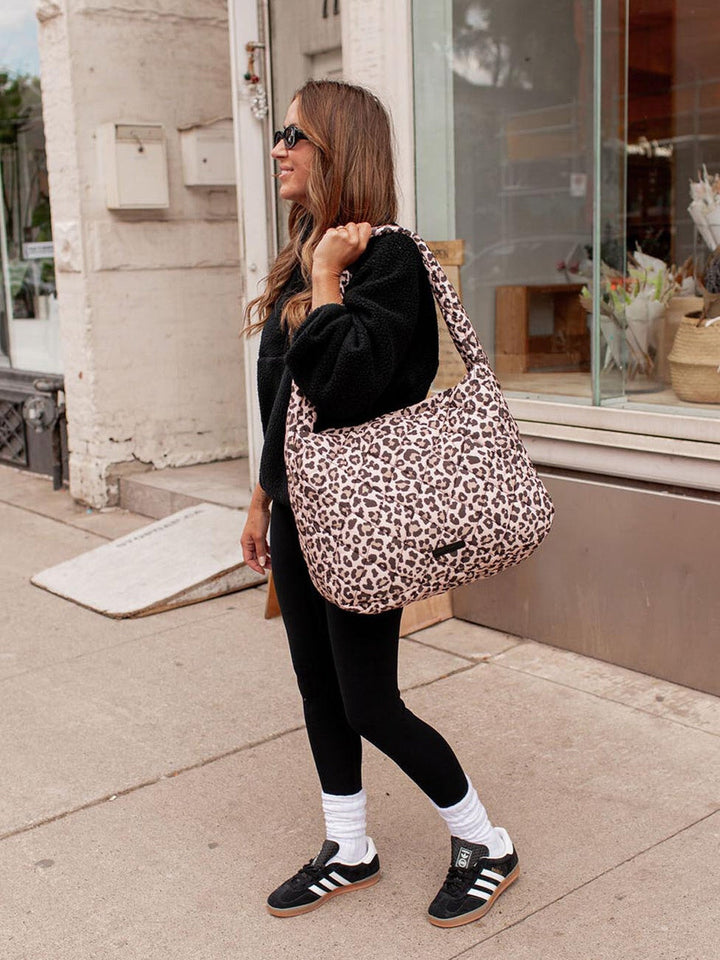 Woman carrying a leopard print hobo bag on a sidewalk
