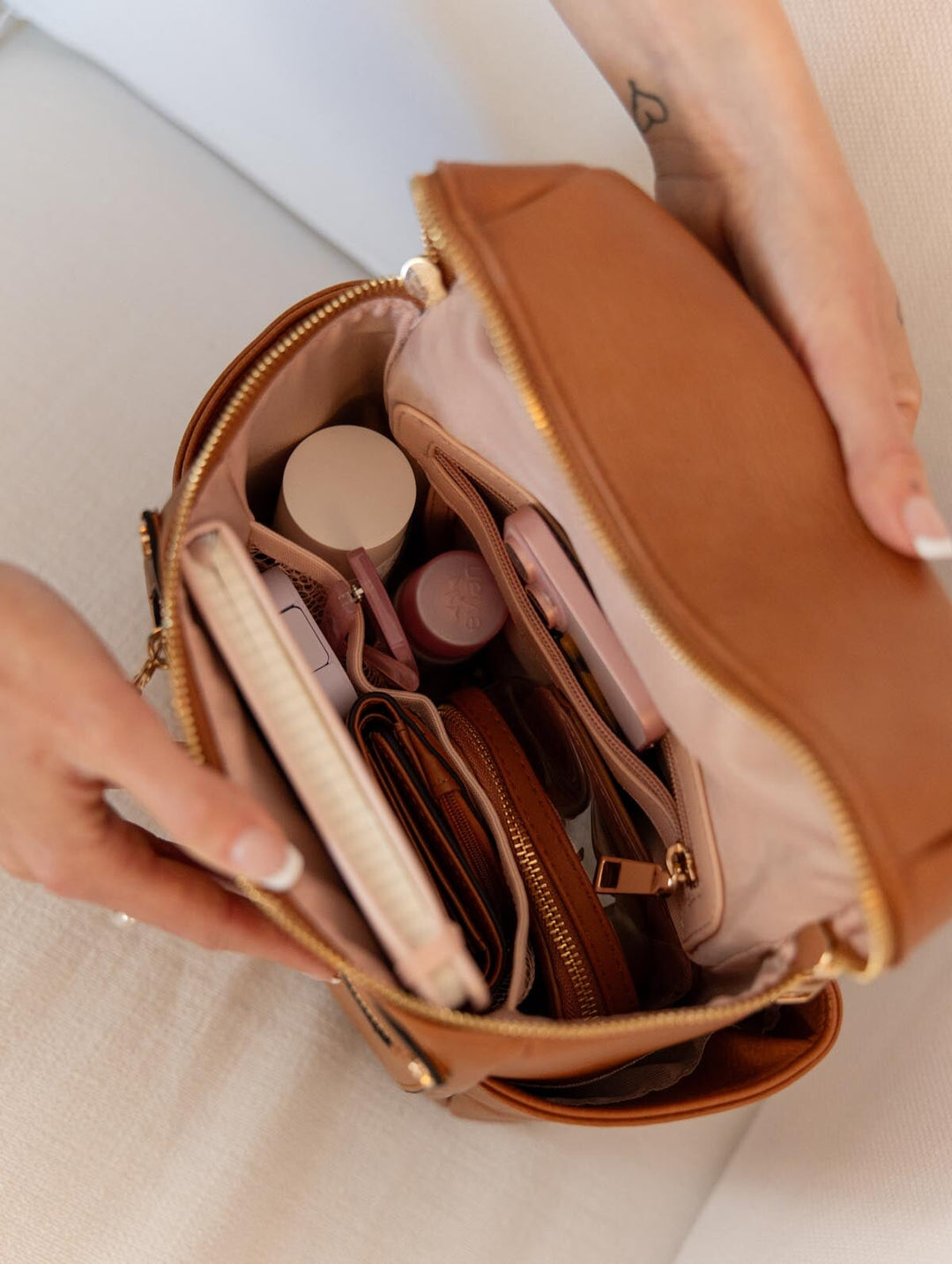 Brown vegan leather backpack containing various items on a light background