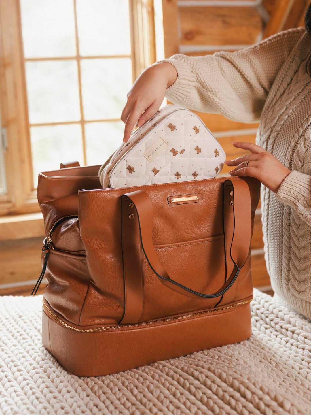 Small white makeup bag being placed inside a vegan leather travel bag