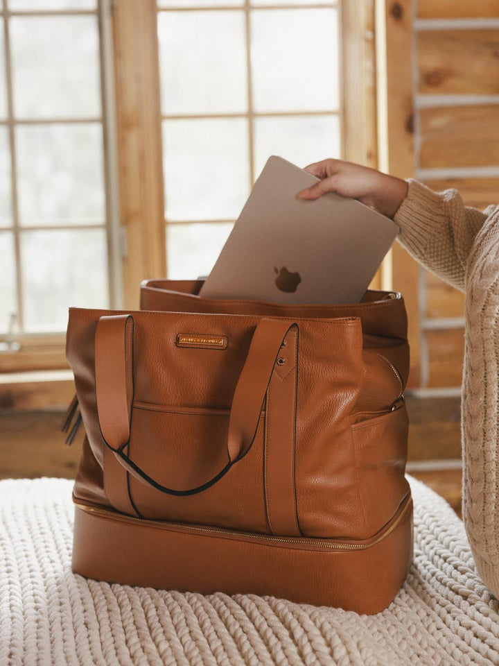 Brown vegan leather bag with a laptop being placed inside