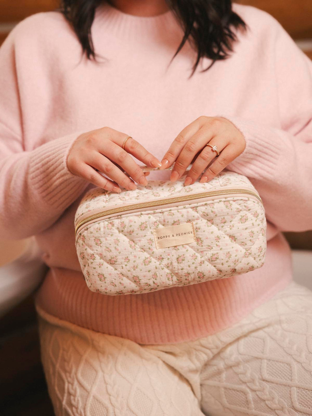 Woman holding a floral patterned cosmetic case 