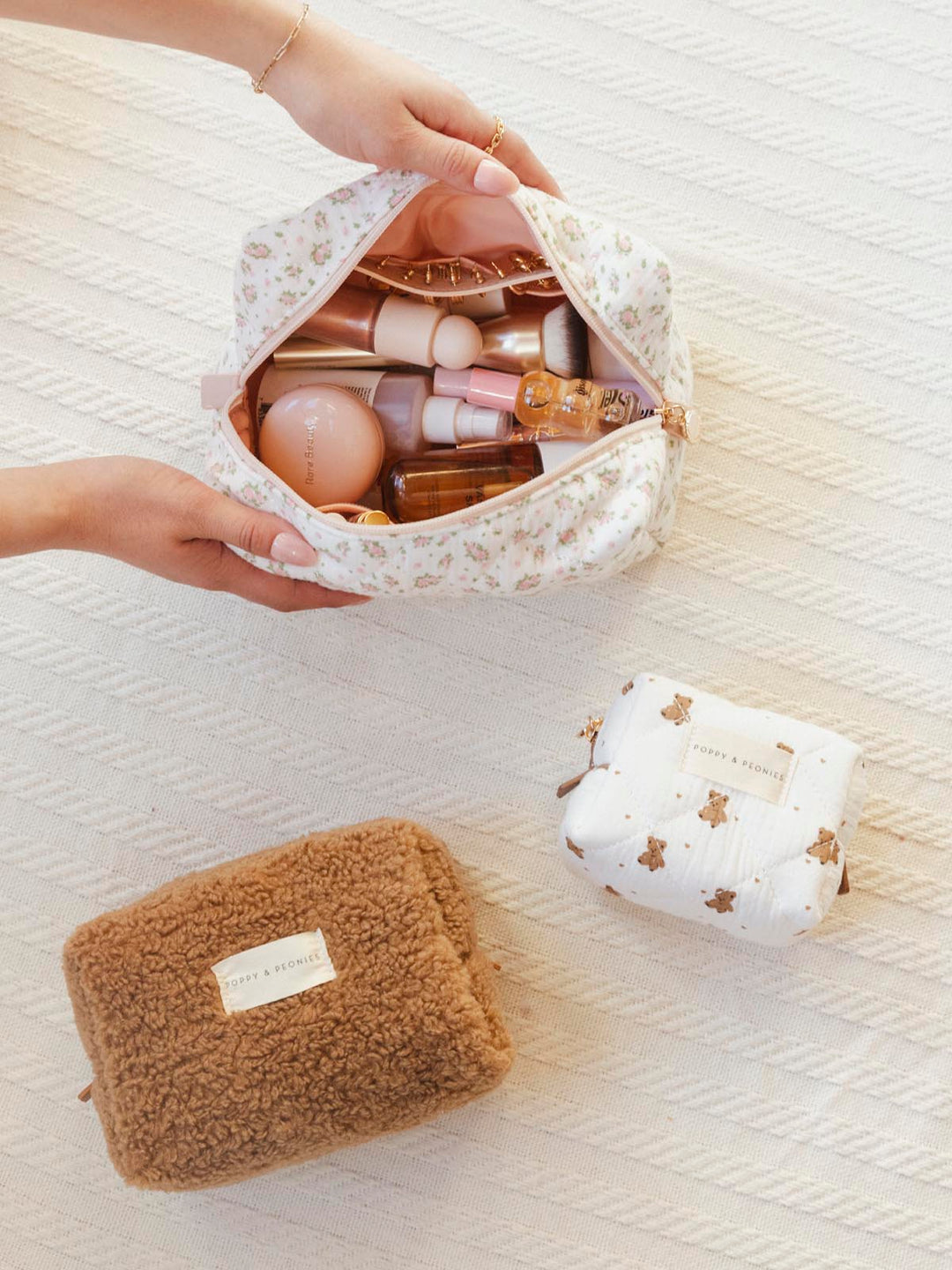 Three makeup bags on a white blanket
