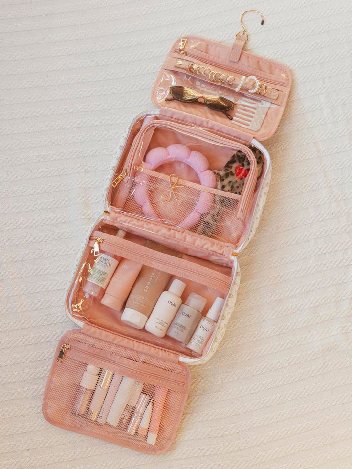 Pink cosmetic bag with various items on a light background