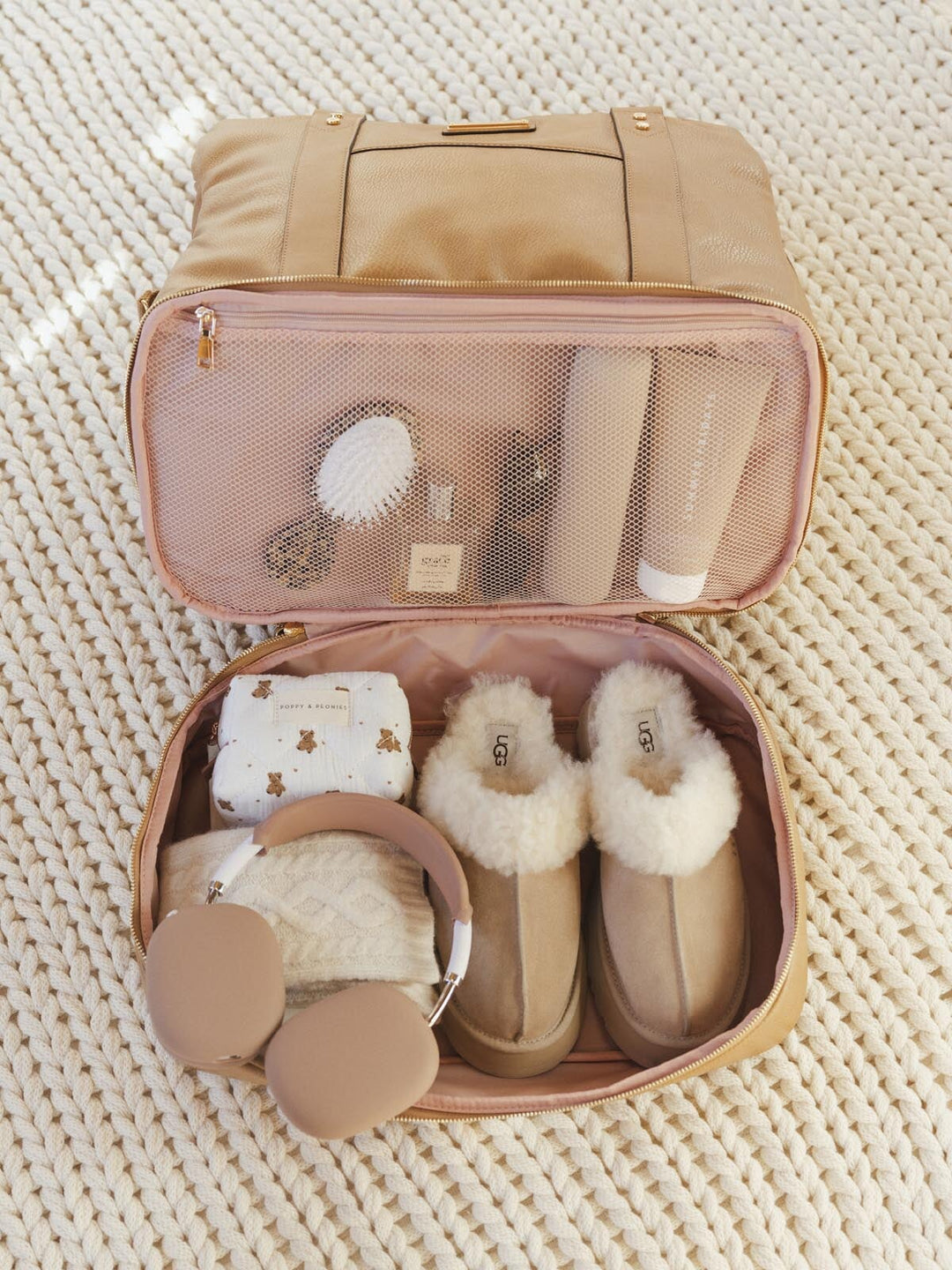 Open vegan leather travel bag with slippers, socks, and headphones.
