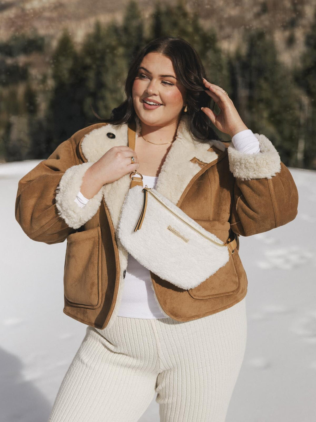 Person wearing a cream faux fur crossbody bag