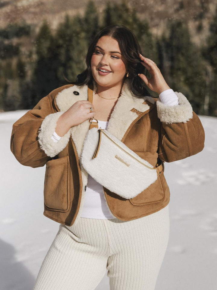 Person wearing a cream faux fur crossbody bag