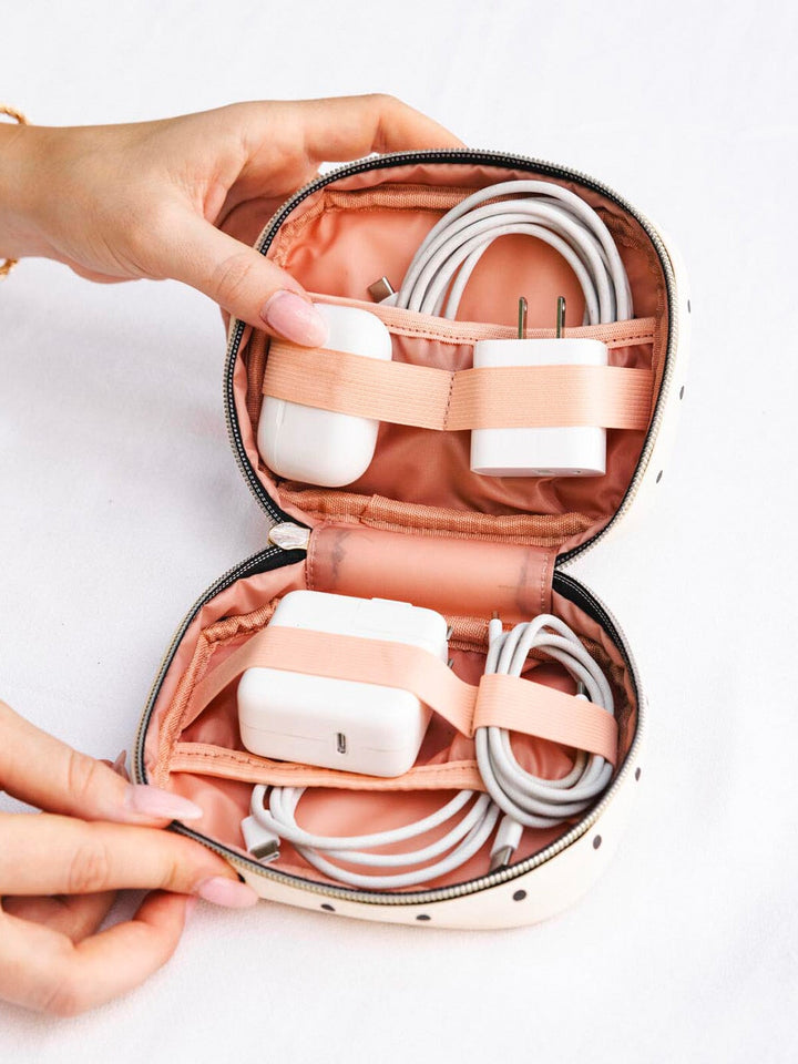 Person holding a pink travel case with electronic accessories