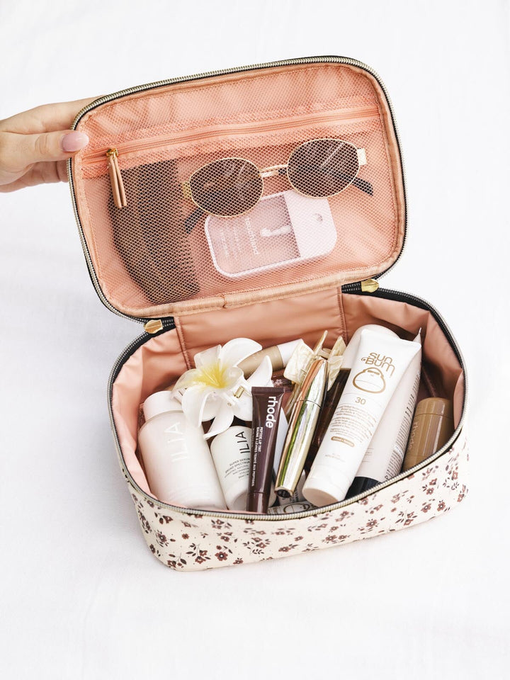 Small travel case with toiletries and sunglasses on a white background