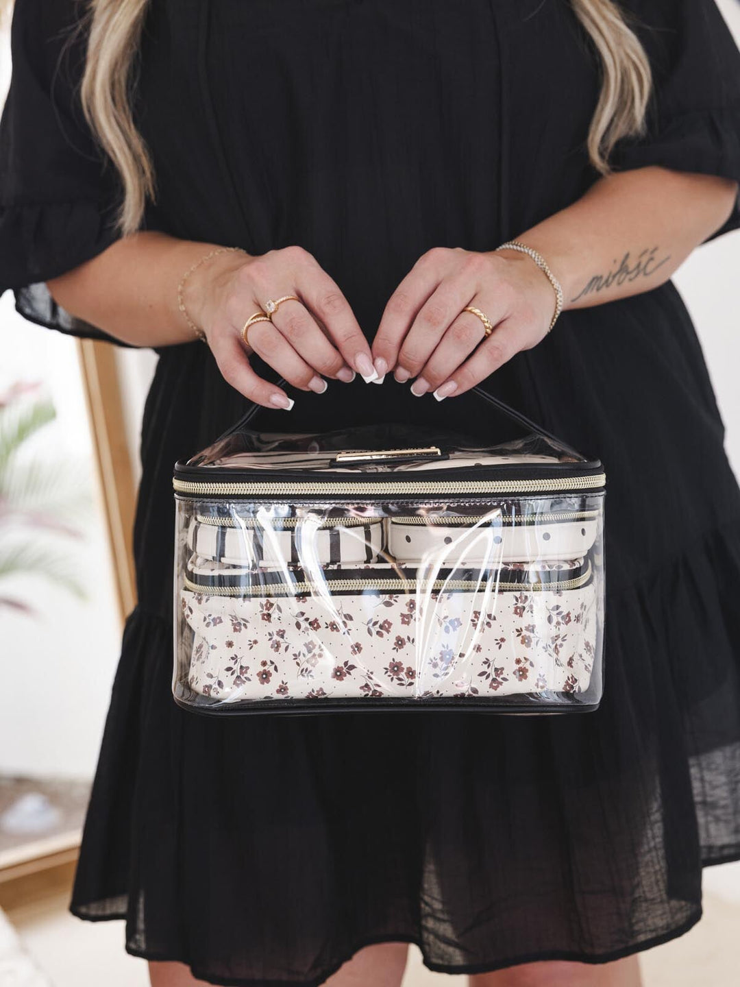 Person holding a cosmetic bag with three smaller cosmetic bags organized inside of it