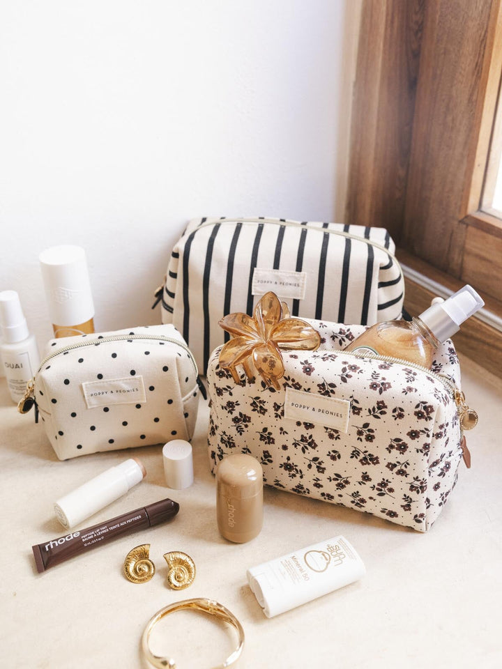 Cosmetic bags with skincare products and accessories on a light surface.