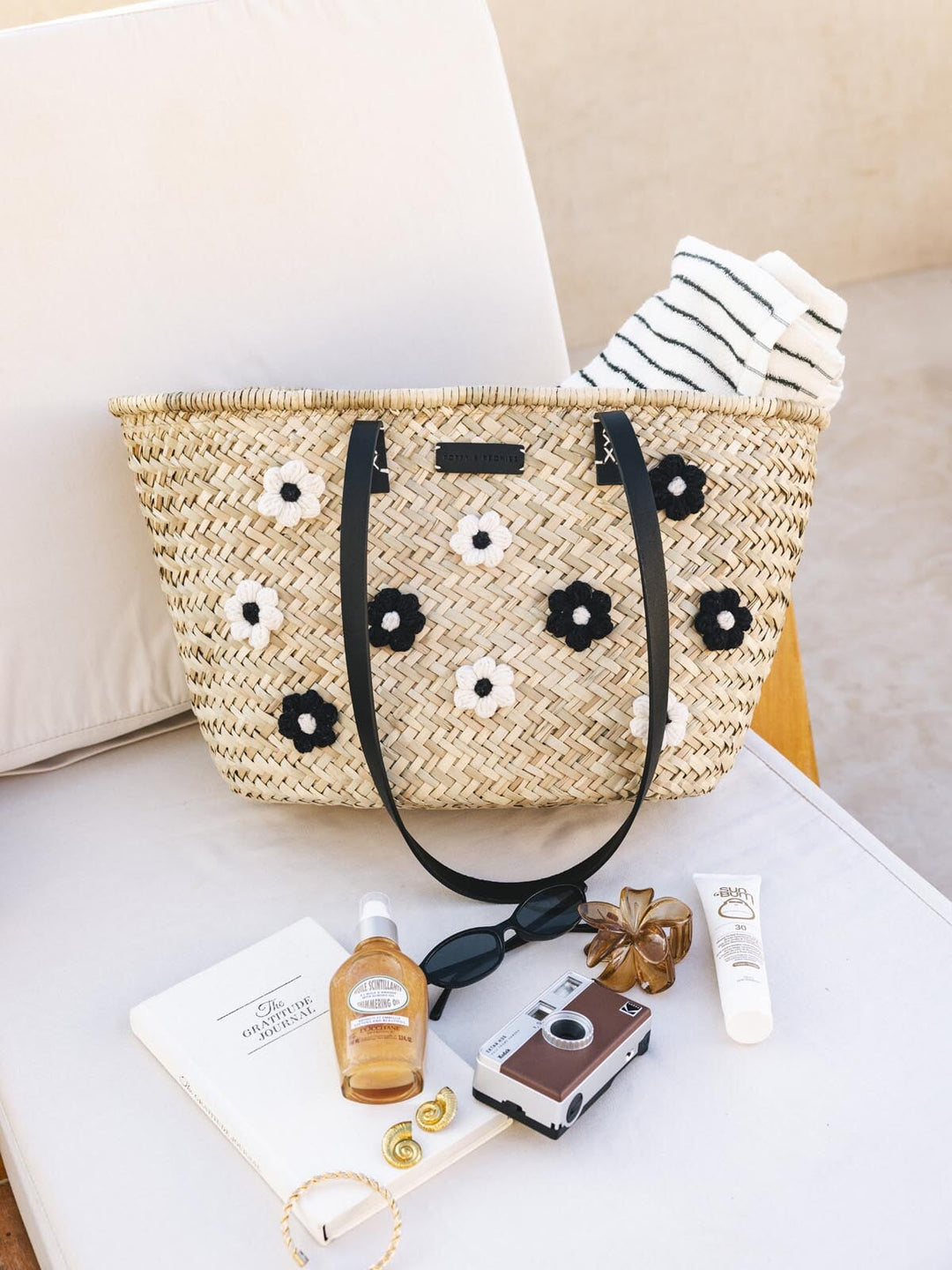 Straw bag with floral adornments on a chair with accessories around