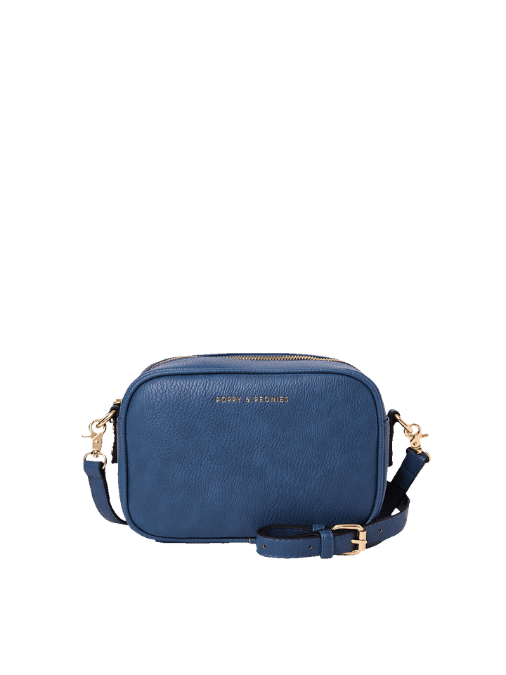 Poppy and Peonies 24/7 Crossbody in Navy, front view of a compact rectangular crossbody bag featuring a rich navy-blue pebbled texture, rounded edges, a top zipper closure, a detachable adjustable strap with gold-tone buckle and clasp hardware, and a subtle gold-tone Poppy and Peonies logo near the top center.