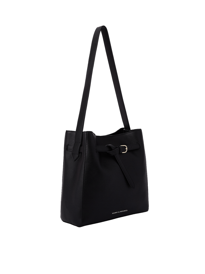 Poppy & Peonies The Knot Shoulder Bag in Black, shown from a three-quarter angle highlighting its structured silhouette, decorative belted buckle, gold-tone hardware, and long shoulder strap.