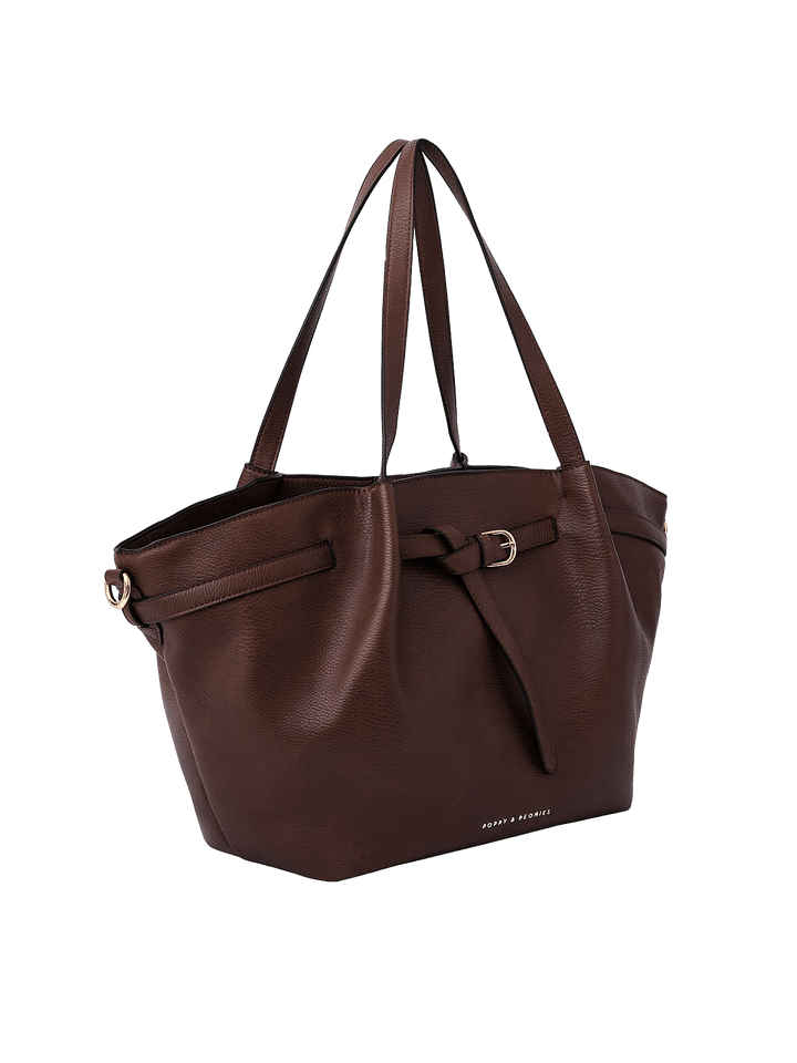 Poppy & Peonies The Knot Tote in Espresso, shown from a three-quarter angle highlighting its roomy trapezoid shape, decorative belted detail, long shoulder straps, and gold-tone hardware.