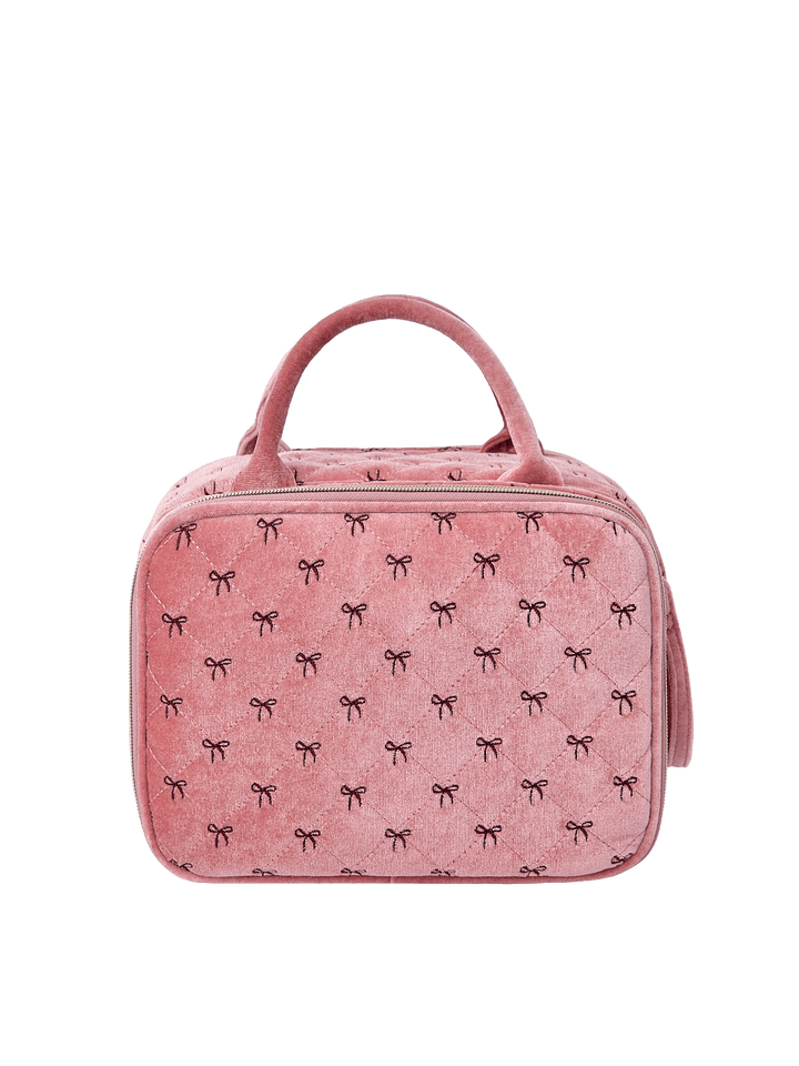 Poppy and Peonies The Routine Cosmetic Pink Velvet displayed from the back, featuring its soft pink velvet exterior with delicate black bow patterns, structured rounded silhouette, dual pink top handles, and zippered closure.