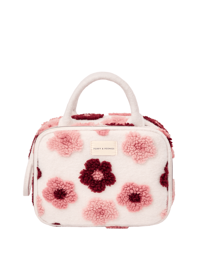 Poppy and Peonies The Routine Cosmetic Floral featuring a structured rounded rectangular silhouette, soft cream-colored exterior with plush pink and berry floral patterns, dual cream top handles, zip-around closure, and rectangular Poppy and Peonies logo plate on the front.