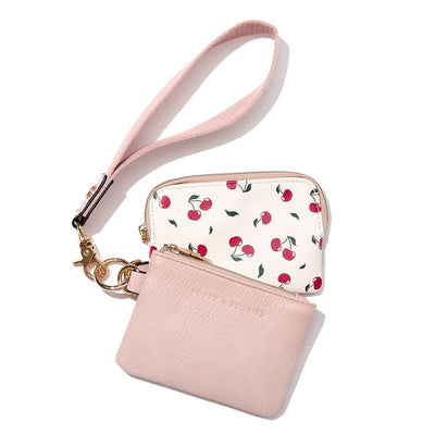 A blush coloured and cherry printed wallet on a wristlet