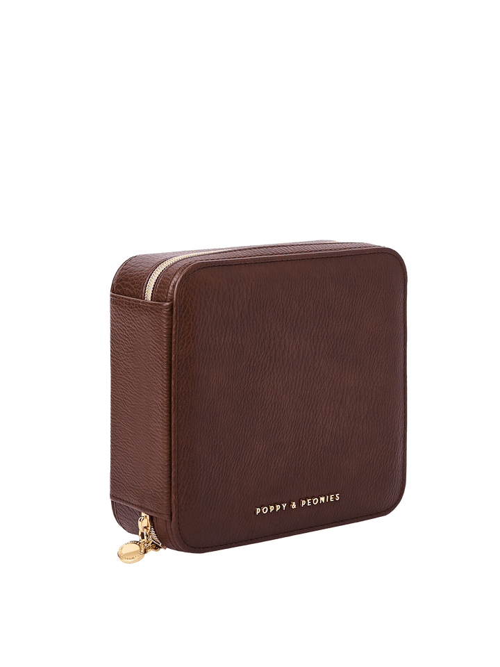 Poppy and Peonies The Out of Office Case Espresso displayed at a three-quarter angle, highlighting its structured square shape, textured espresso exterior, gold-tone zip-around closure, round zipper pull, and subtle Poppy and Peonies logo near the bottom.