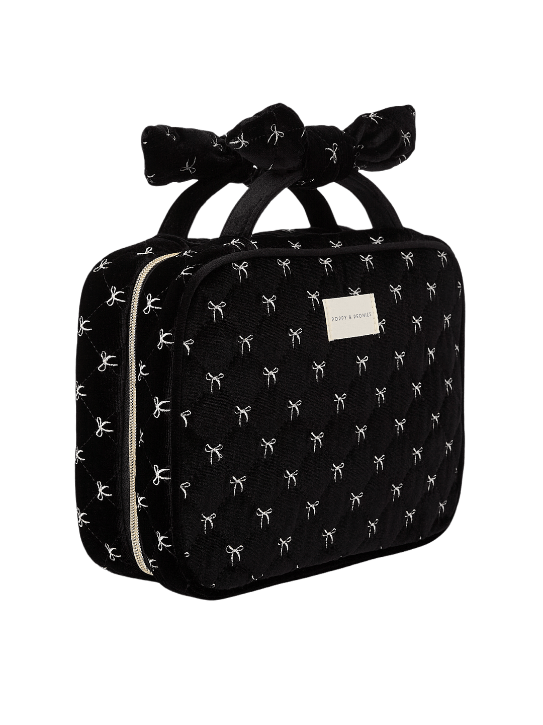 Poppy and Peonies Hook Me Up Cosmetic Case Black Velvet displayed at a three-quarter angle, highlighting its structured rectangular shape, soft black velvet exterior with white bow patterns, decorative bow-shaped top handle, zip-around closure, and rectangular gold logo plate.