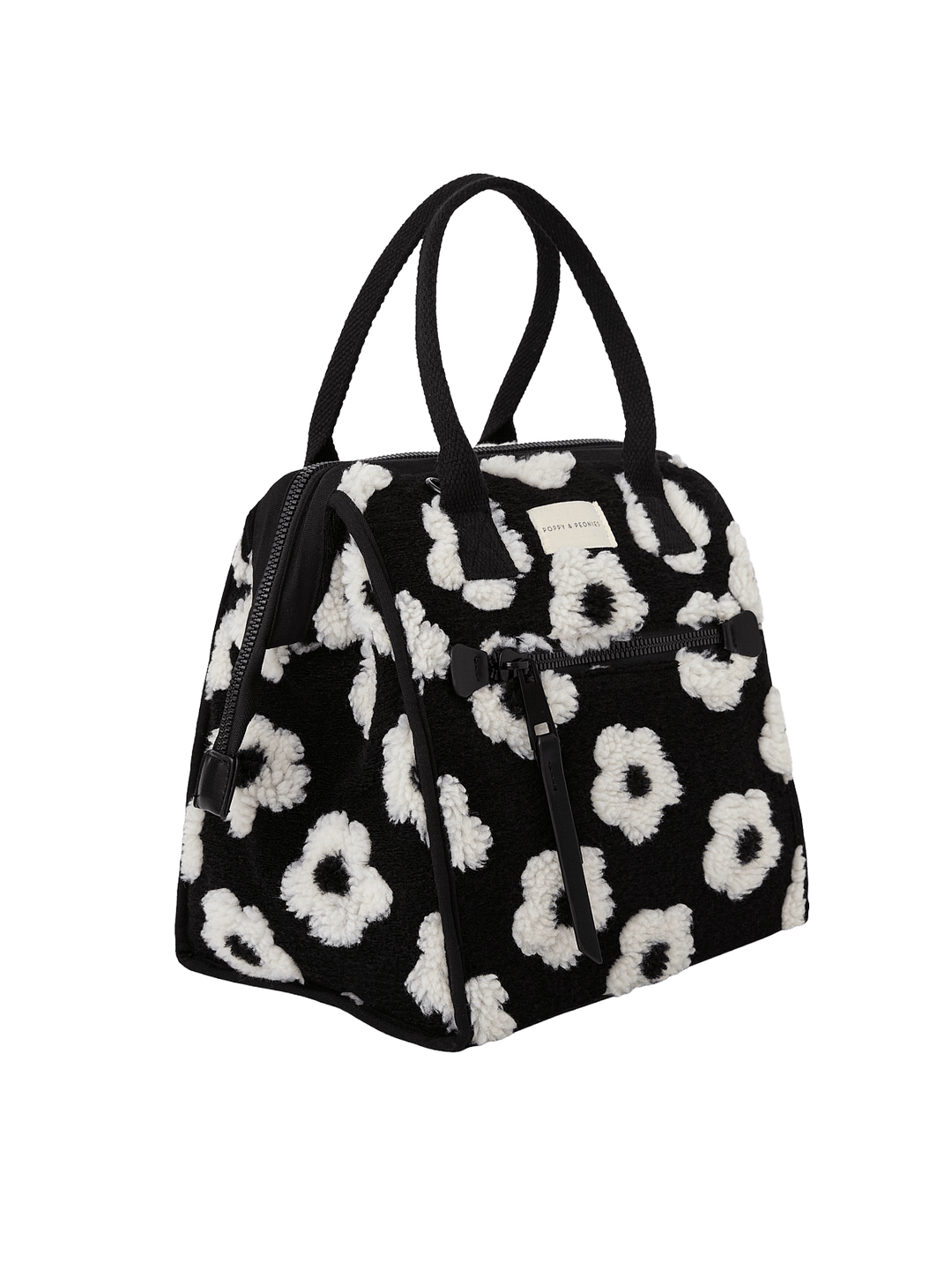 Poppy and Peonies The Lunch Bag Black Floral displayed at a three-quarter angle, highlighting its structured silhouette, black exterior with white floral patterns, dual top handles, and spacious side profile.