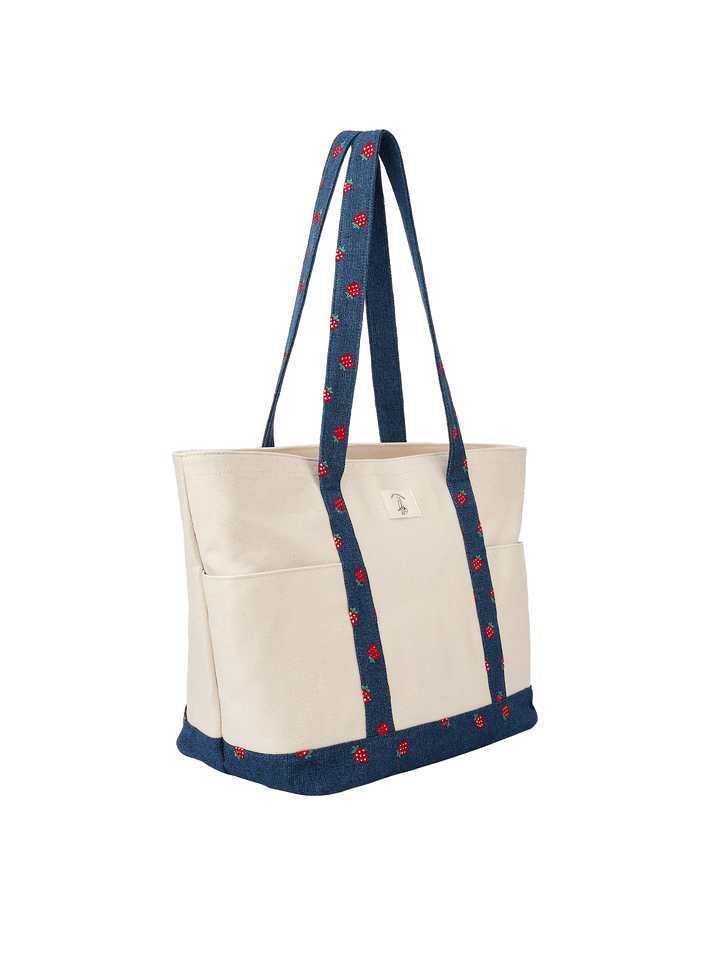 Poppy & Peonies Analog Tote in Strawberry Denim angled side view, featuring cream canvas, navy strawberry-print straps and coordinating base trim.