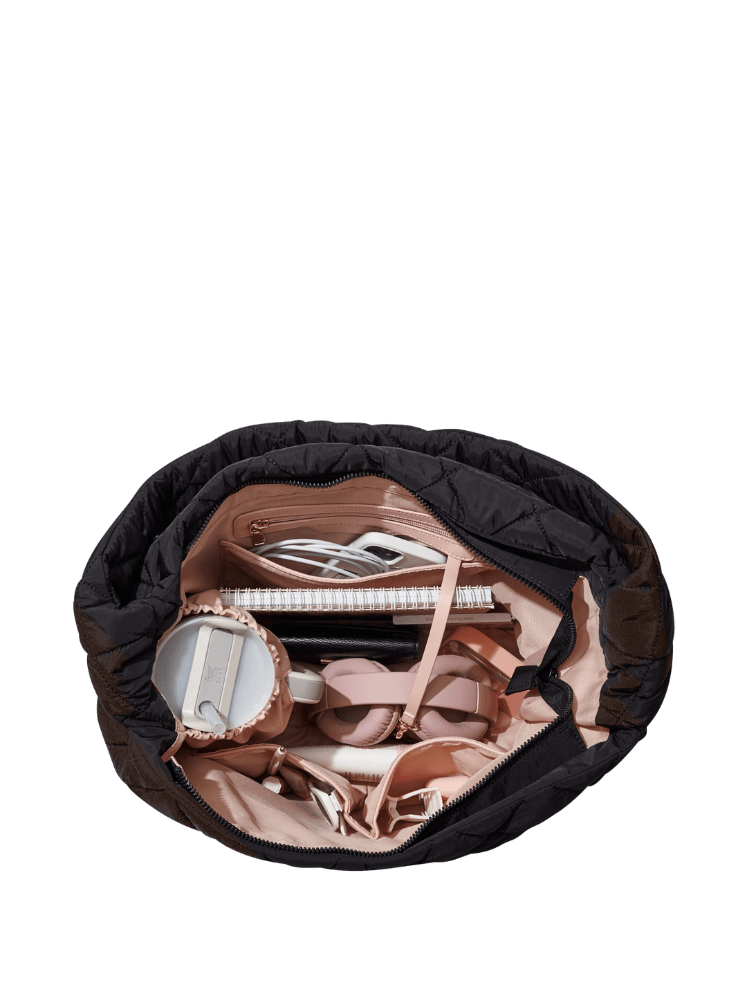 Black quilted hand bag with various shoes and a notebook on a transparent background