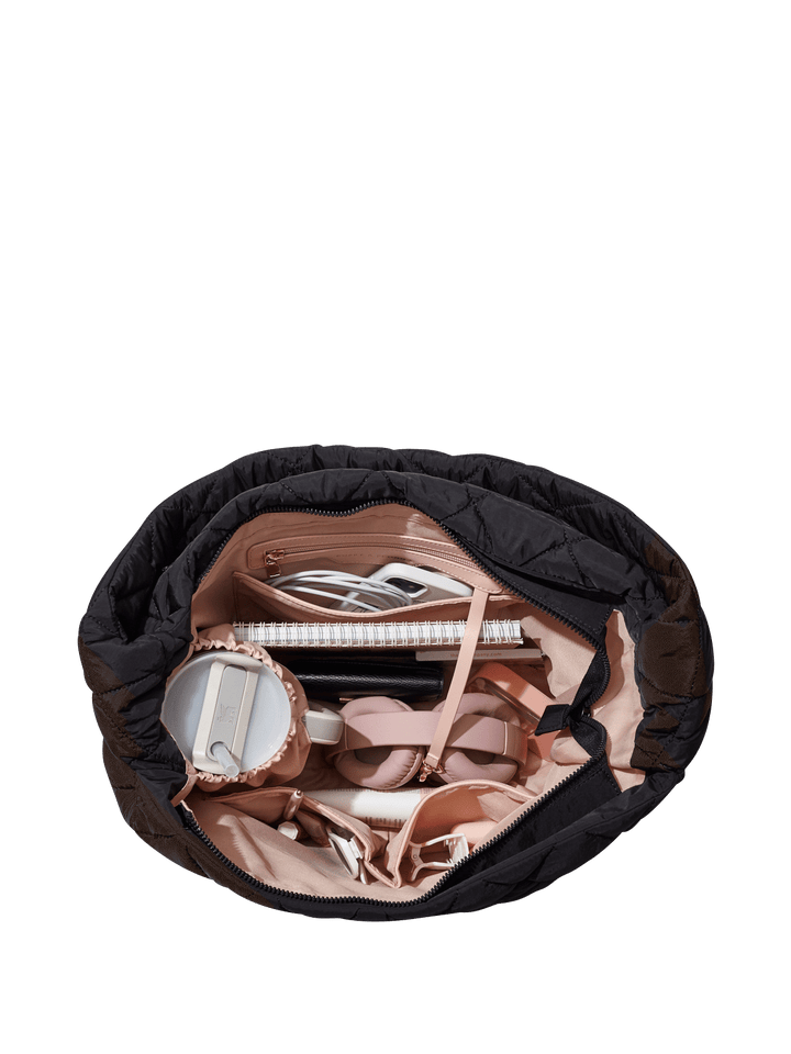 Black quilted hand bag with various shoes and a notebook on a transparent background