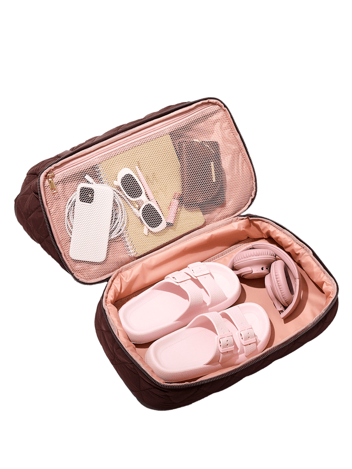 Pink sandals in an open travel pouch with sunglasses and shoes
