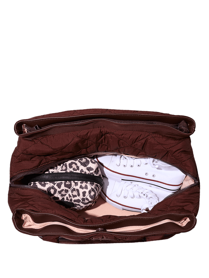Brown travel bag with a leopard print pouch and white sneakers inside on a transparent background