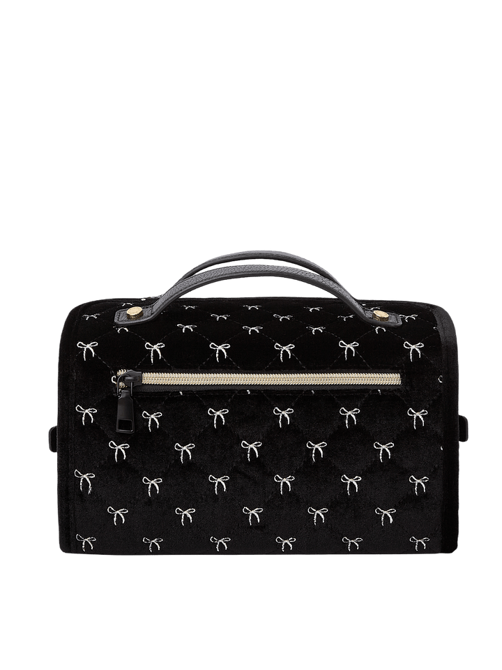 Poppy and Peonies The Glam Squad Cosmetic Case Black Velvet displayed from the back, featuring its soft black velvet exterior with delicate white bow patterns, structured rectangular silhouette, dual top handles, horizontal zippered pocket, and gold-tone hardware.