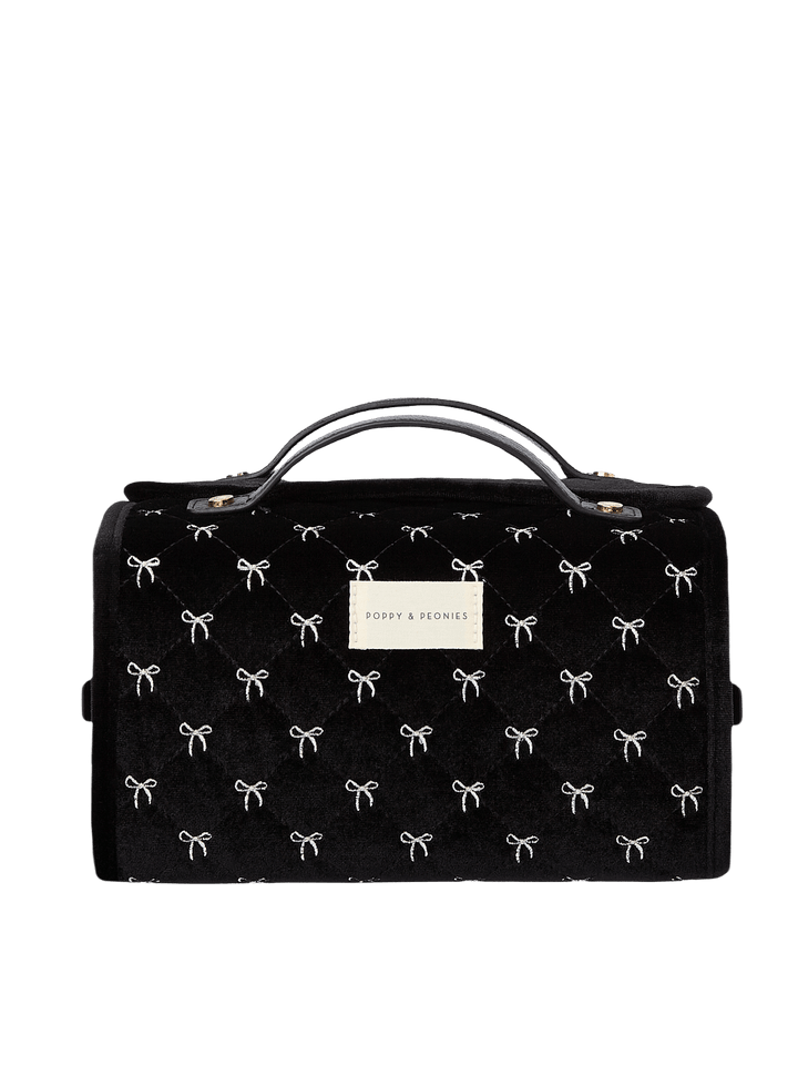 Poppy and Peonies The Glam Squad Cosmetic Case Black Velvet featuring a structured rectangular silhouette, soft black velvet exterior with delicate white bow patterns, dual top handles, zip-around closure, and rectangular gold Poppy and Peonies logo plate on the front.