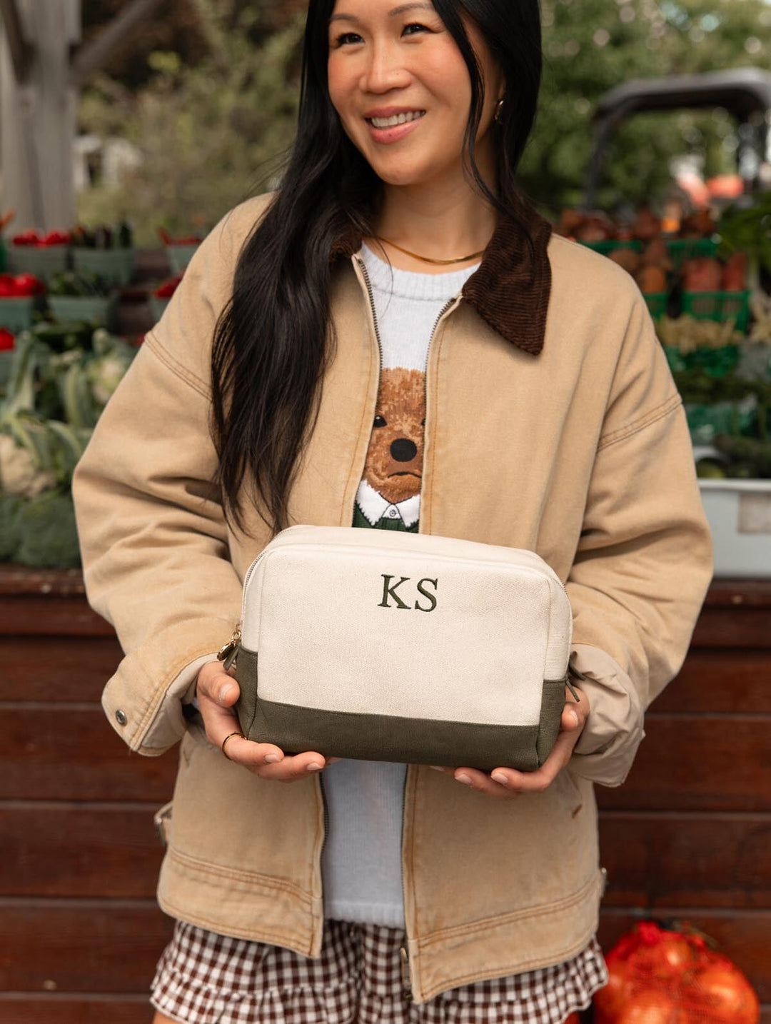 Poppy & Peonies The Double Take Cosmetic in Olive featuring KS initials on the cream exterior, held by a woman in a tan jacket and gingham bottoms.