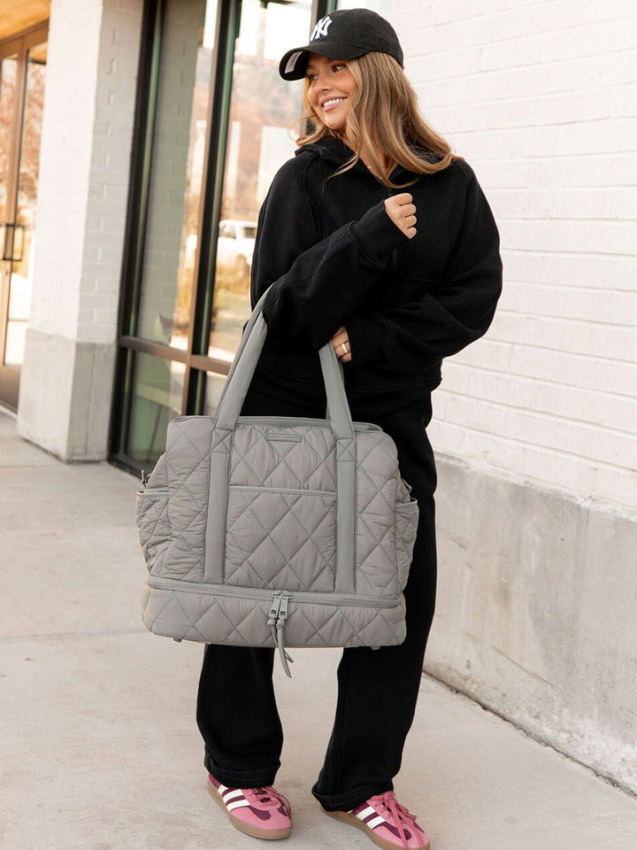 Woman holding a grey quilted bag outdoors