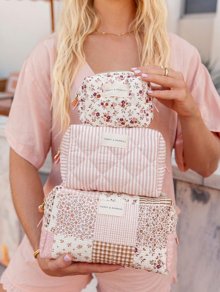 Person holding three floral-patterned cosmetic cases