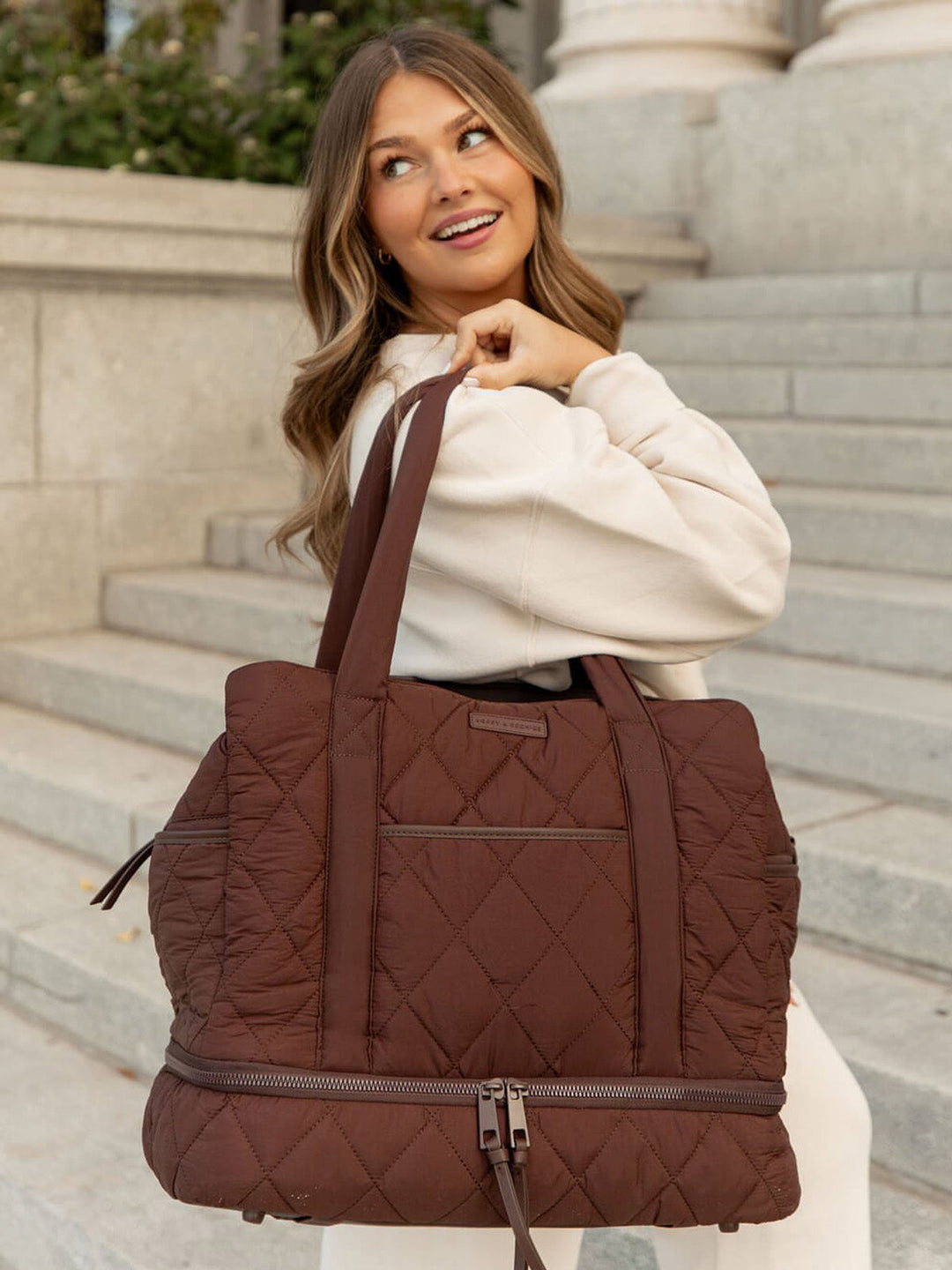 Woman holding a brown quilted bag on stone steps