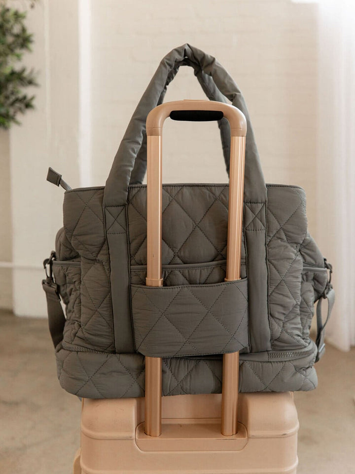Grey quilted bag with a trolley sleeve on a suitcase