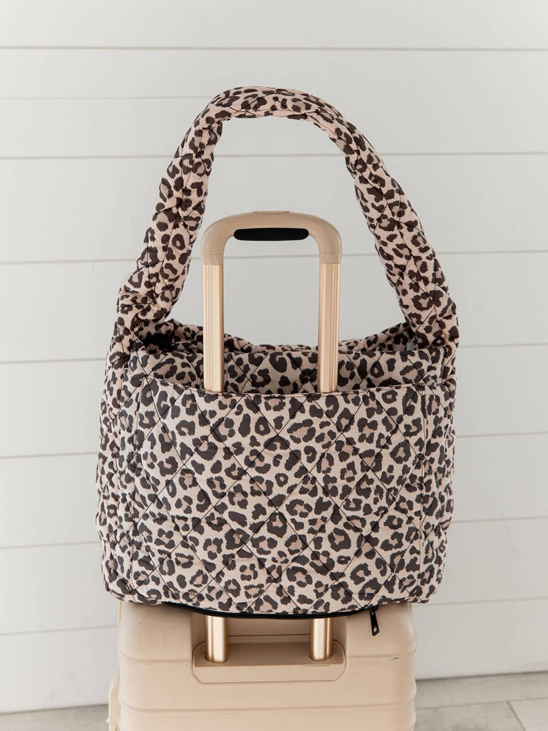 Quilted leopard print bag with a trolley sleeve on a suitcase