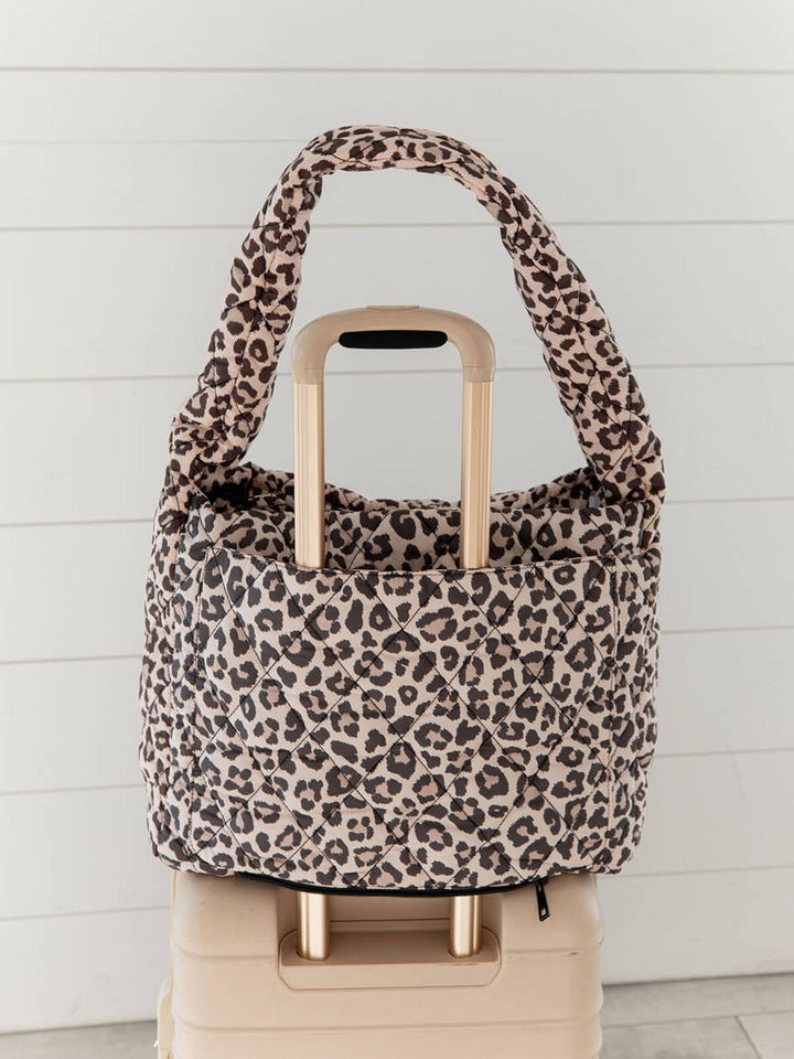 Quilted leopard print bag with a trolley sleeve on a suitcase