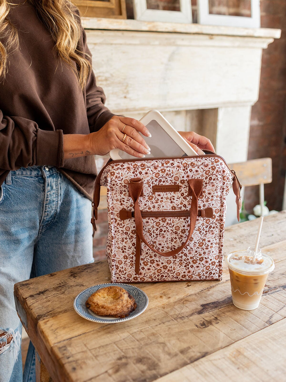Person holding a floral-patterned lunch bag.